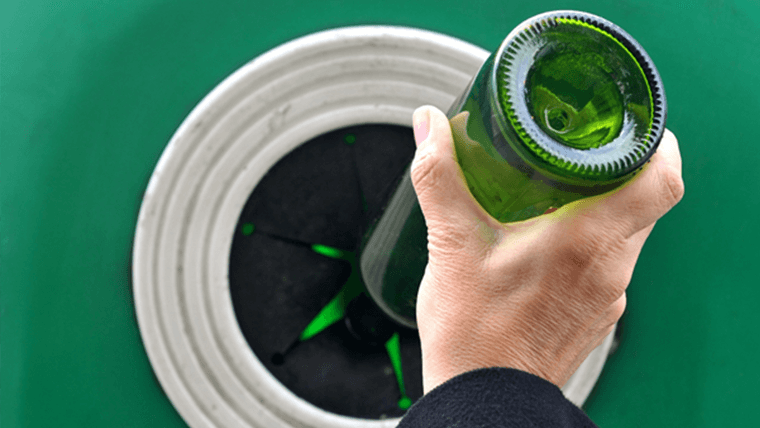 Szklana zielona butelka wrzucana do śmietnika na szkło - Recycling – co to jest?