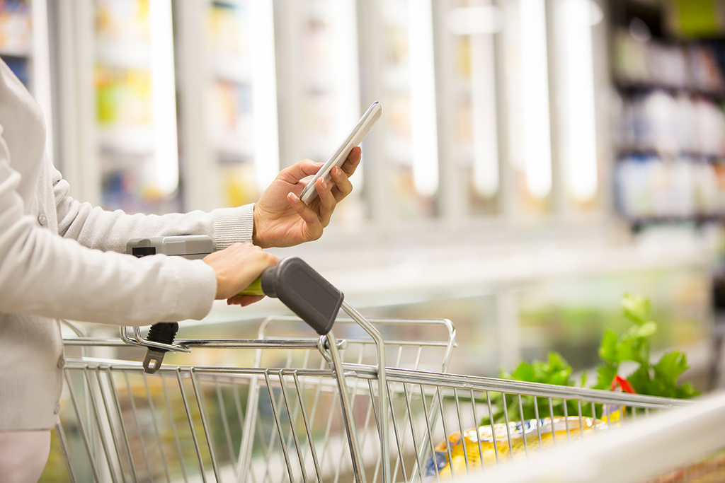 Kobieta w supermarkecie korzystająca z listy zakupów w telefonie - Jak kupować bardziej eko