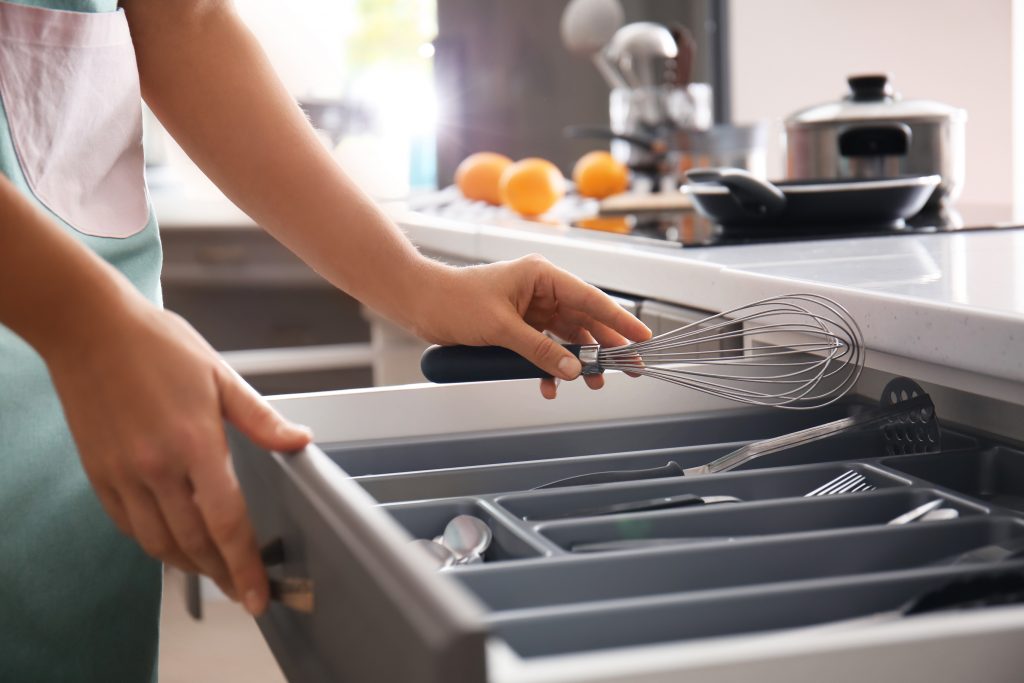 Kobieta wkłada trzepaczkę do szuflady kuchennej- Minimalizm w domu - najlepsze tricki