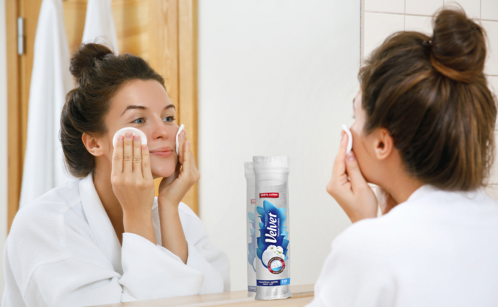 Odbicie w lustrze kobiety zmywającej makijaż przy użyciu płatków kosmetycznych Velvet Comfort – Domowe SPA