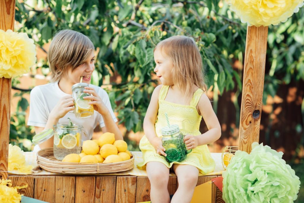 Chłopiec i dziewczynka pijący lemoniadę w ogrodzie –- Przepisy na orzeźwiające lemoniady