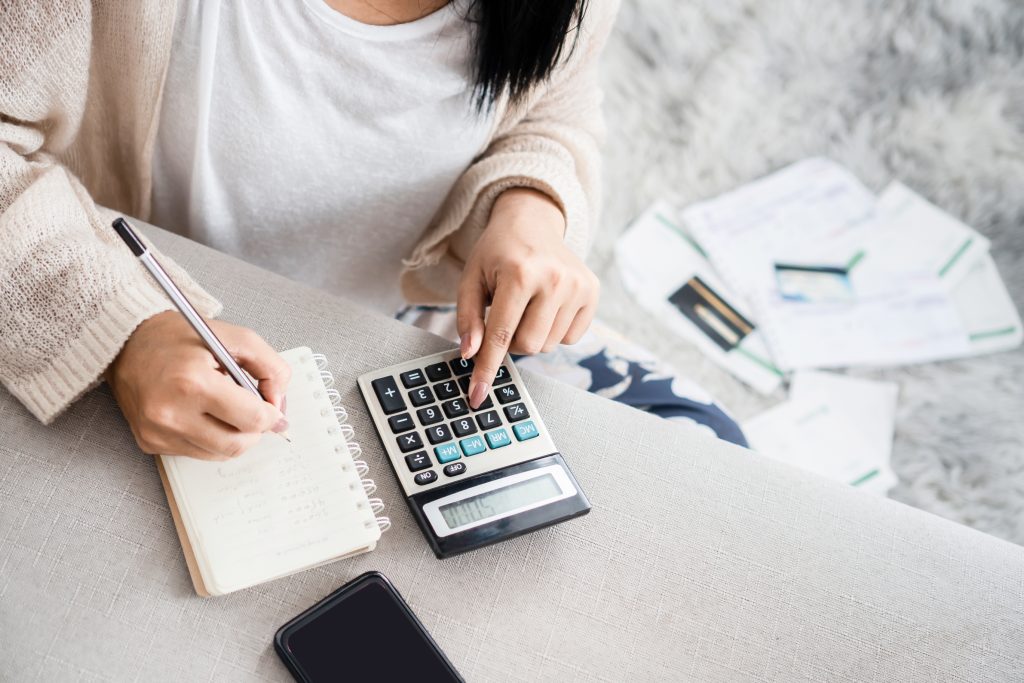 Jak oszczędzić na zakupach - kobieta liczy na kalkulatorze i robi notatki